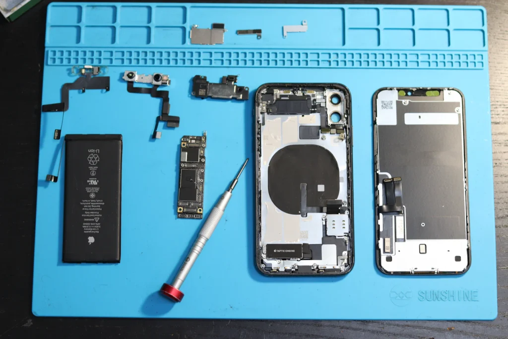 Composants d’un iPhone démontés et alignés sur un tapis antistatique