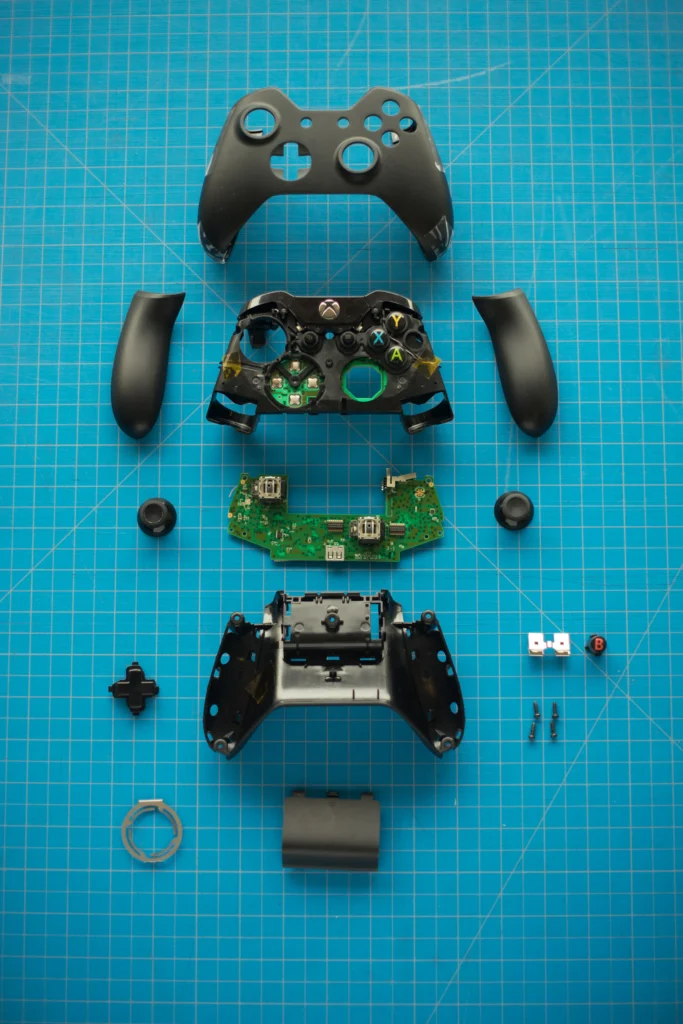 Manette de console démontée, pièces disposées sur un tapis bleu