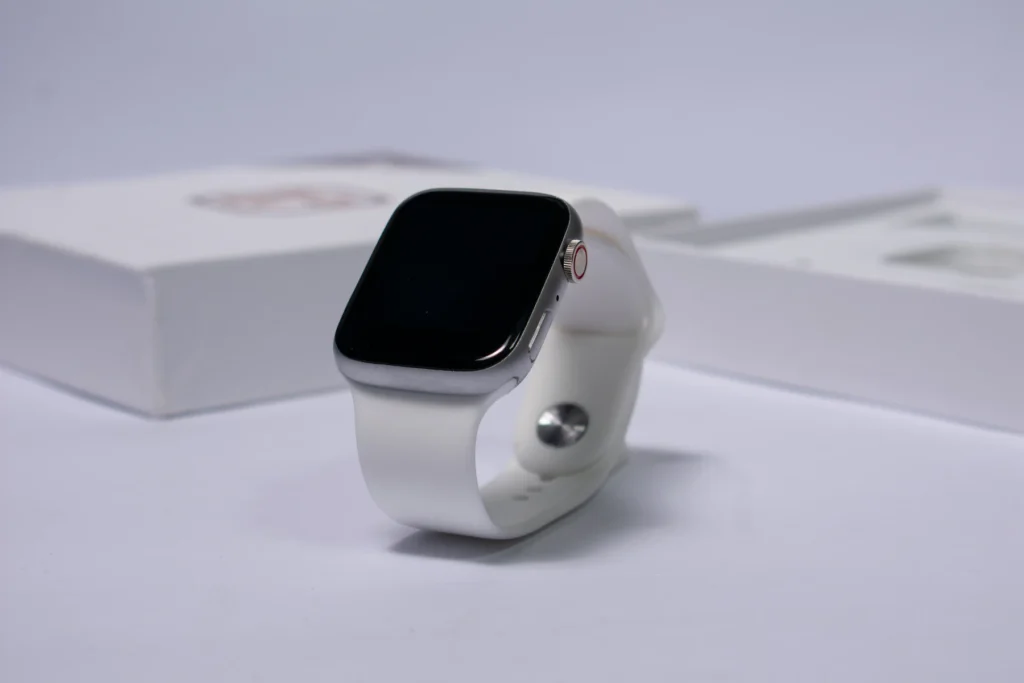 Montre connectée à bracelet blanc posée devant sa boîte
